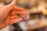 Vintage bronze lizard pendant held in hand, showing its handmade texture and scale.