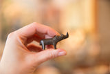 The miniature vintage bronze rhino held in a hand to demonstrate its small scale.