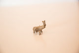 Side profile of a miniature handmade bronze elephant showing its dusty, textured patina.