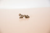 Side profile of a vintage cast bronze chameleon charm showing its textured surface.