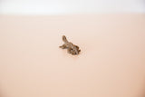 Side view of a vintage cast bronze chameleon charm, highlighting its textured surface.