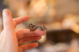 Textured vintage African bronze chameleon pendant resting on fingers.