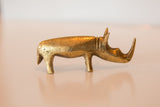 Side view of vintage African bronze rhino sculpture with textured golden patina.
