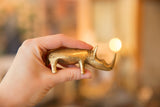Hand holds vintage African bronze rhino, highlighting handmade texture and golden patina.