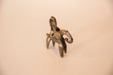 Vintage African bronze sculpture detail: warrior figure with spiral motif and aged patina.