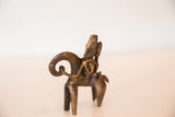 Textured bronze African warrior figure with coiled details on a riding animal.