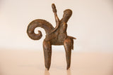 Profile view of a bronze warrior riding a stylized animal with a curled tail.