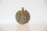 Vintage African bronze gecko medallion standing upright on its textured, coiled edge.