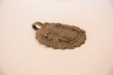 Angled view of the vintage bronze medallion highlighting the raised gecko and coiled texture.