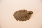 Angled profile of the bronze gecko medallion showing its textured surface and integrated loop.