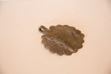 Angled view of the vintage bronze crocodile medallion showing its surface texture.