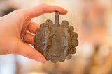 Vintage bronze crocodile medallion held in hand to demonstrate its size and texture.