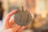 Vintage bronze chameleon medallion held to show its handcrafted texture and scale.