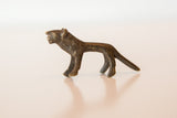 A miniature African bronze lion in profile, highlighting its stylized handmade form and dark patina.