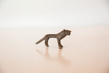 Side profile of a vintage bronze lion showing its elongated, handmade form.