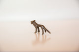 Side profile of the small African bronze lion showing its slender, hand-cast form.