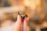 A hand holding a tiny collectible bronze elephant, possibly an Ashanti gold weight.