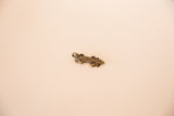 Angled profile of a vintage African bronze lizard pendant showing its form.