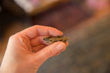 Vintage bronze lizard pendant held between fingers to show its small scale.