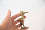 Small African bronze stork sculpture with incised details held in hand for scale.