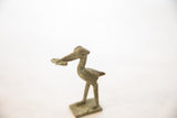 Side profile of a handmade bronze stork figure with an aged patina holding a fish.