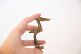 Vintage bronze stork figurine with a textured body, held to show scale.