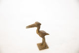 Detailed view of an African bronze stork's head showing aged patina and circular eye motif.
