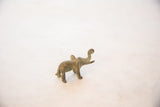 Profile of a small oxidized bronze elephant showing its rounded form and curled trunk.