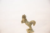 Side profile of a vintage bronze rooster highlighting its stylized comb and oxidized finish.