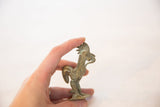 A hand holds the small vintage oxidized bronze rooster, showing its collectible scale.