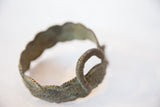 The coiled handle and intricate etched patterns of the handmade vintage bronze bracelet.