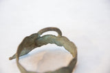 The arched detail and rustic, handmade texture of a vintage bronze bracelet.