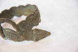 Incised details and textured patina on the head of a vintage bronze snake bracelet.