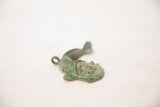 Angled view of the vintage copper fish pendant with a rustic, oxidized patina.