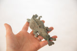 The small, vintage oxidized copper crocodile sculpture held in an open palm.