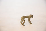 Side view of a vintage handmade bronze monkey with aged green-brown patina.