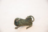 The vintage copper feline's arched back and curled tail with a green oxidized patina.
