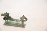 Textured green and brown patina on the side profile of a vintage copper dragon figurine.