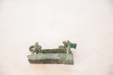 Close view of the handmade copper dragon's base showing its aged, oxidized green patina.