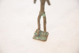 The square base and detailed feet of a copper figure showing heavy blue-green oxidation.