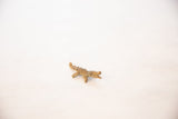 Angled view of a vintage oxidized bronze crocodile pendant showing its handmade form.