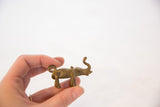 Vintage African oxidized bronze elephant pendant, side view held by hand.