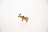 Three-quarter view of a vintage bronze elephant pendant highlighting its handmade form and curled tail.