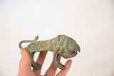 Hand holding a vintage African oxidized copper wild animal, showing textured green patina.