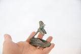 Vintage African copper person figurine held in hand, showing its small scale and profile.