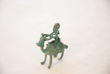 Side view of a vintage African copper figurine highlighting the rider's form and posture.