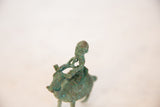 Close-up on the vintage African rider, highlighting its green oxidized copper patina.