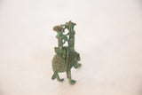Frontal view of a vintage African oxidized copper sculpture of a person riding an animal.