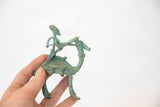 Vintage African copper sculpture with green patina, held to demonstrate its small size.