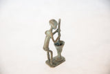 Angled view of the vintage African figurine's oxidized copper surface and form.